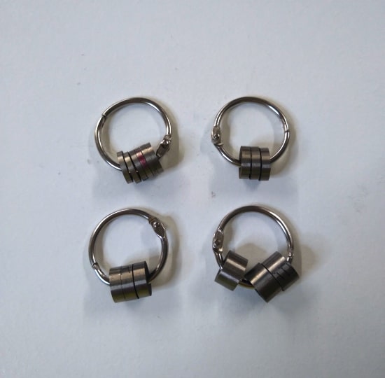 A set of four Ski-Doo pDrive pivot weight spacers on a white surface, perfect for organizing ski gear.