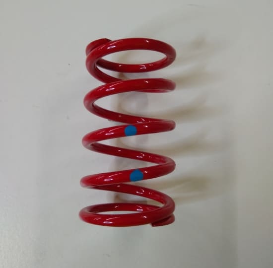 A red spring on a white surface with Ski-Doo TRA Clutch Spring Red/Blue.