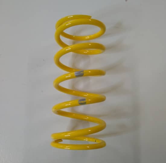 A Ski-Doo TRA Clutch Spring Yellow/Silver, specifically a Ski-Doo TRA Clutch Spring Yellow/Silver, rests on a white surface.